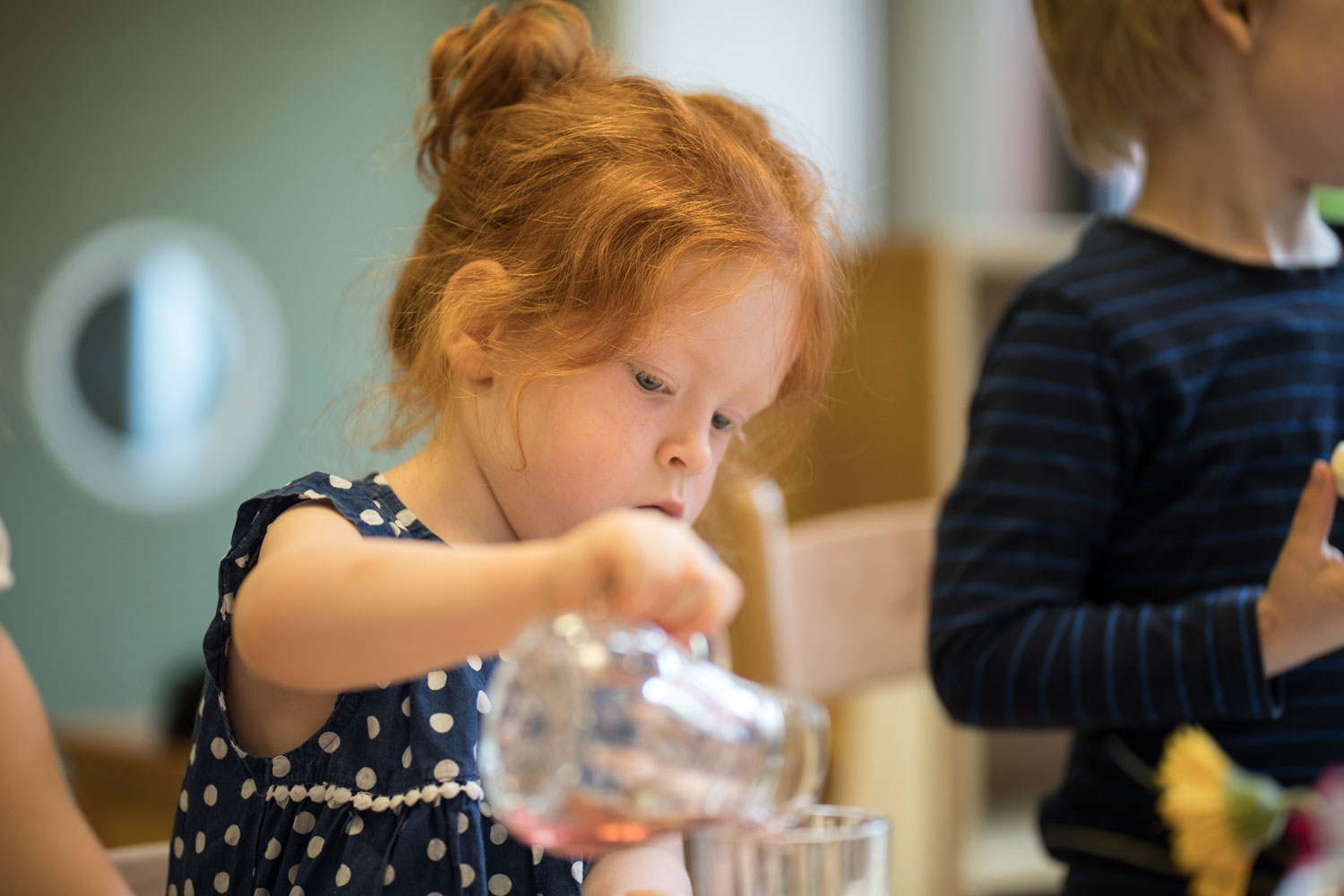 Kind schenkt Wasser aus Karaffe